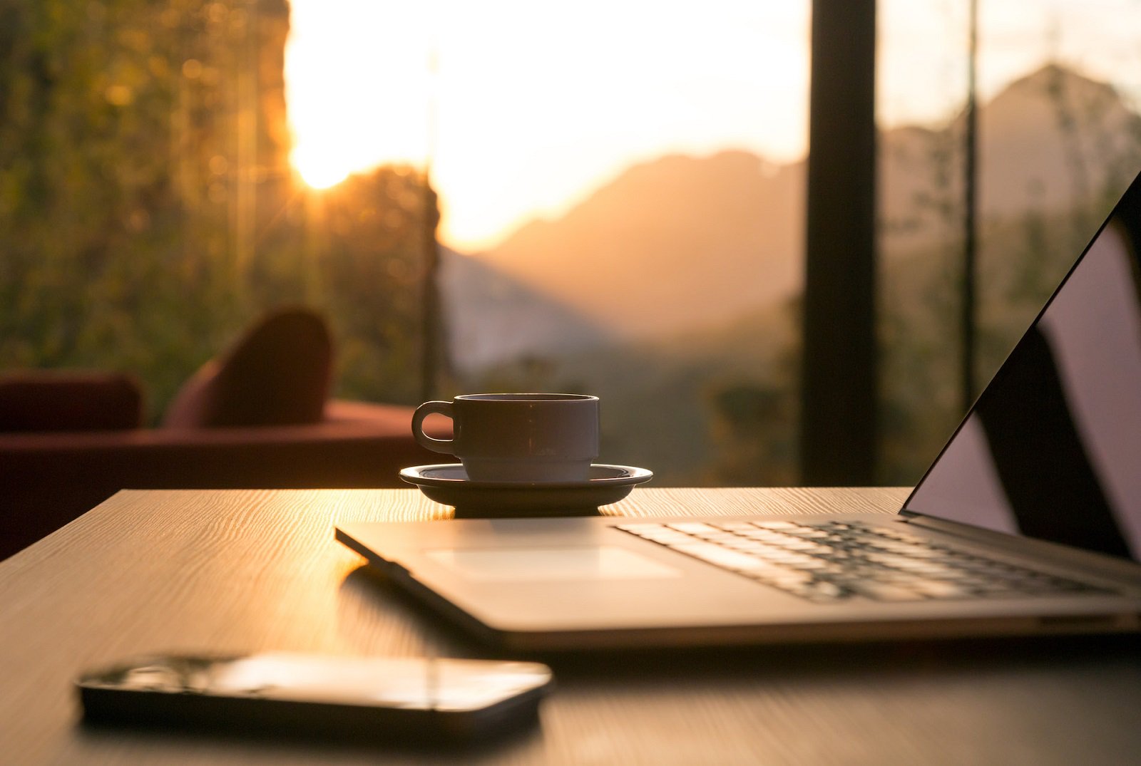 Laptop phone and mug of coffee in a sunset