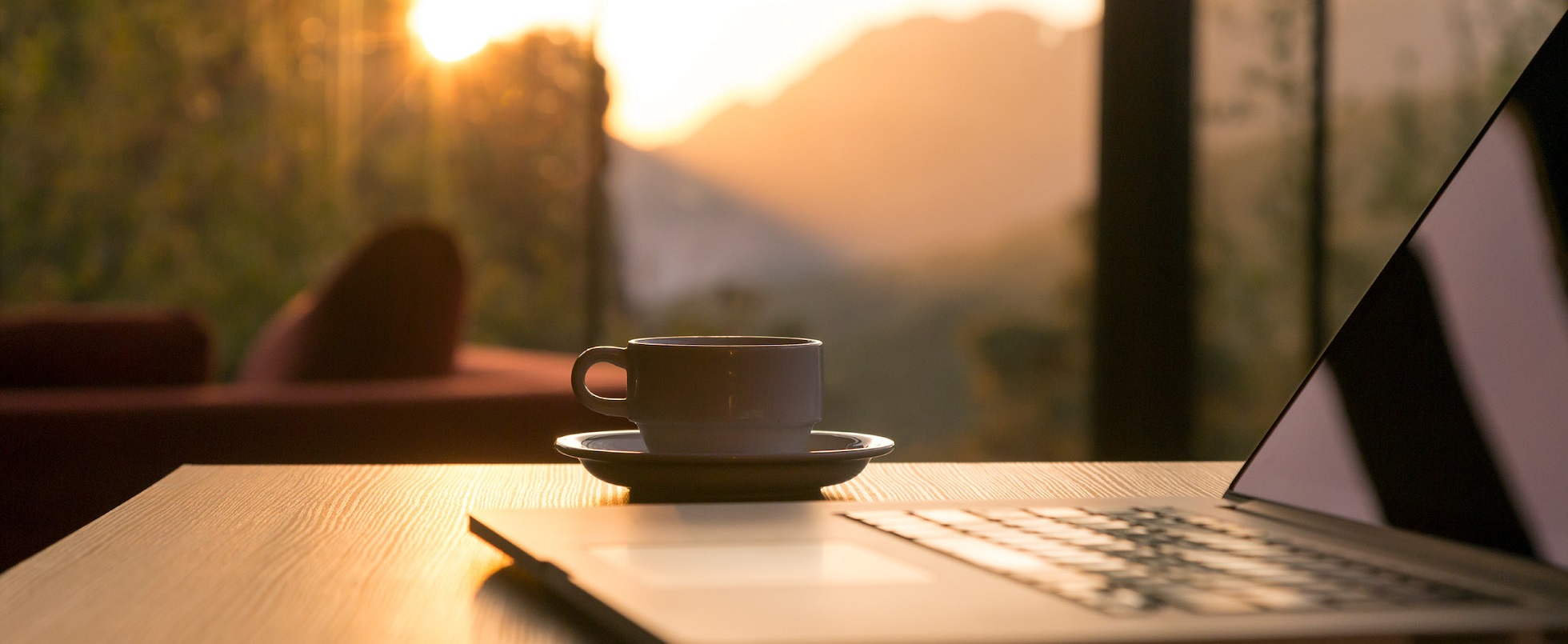 Laptop and mug of coffee in a sunset