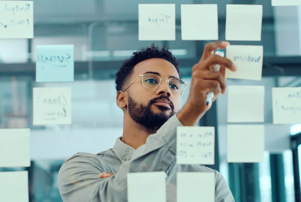Guy looking at post multiple post-it notes on the wall