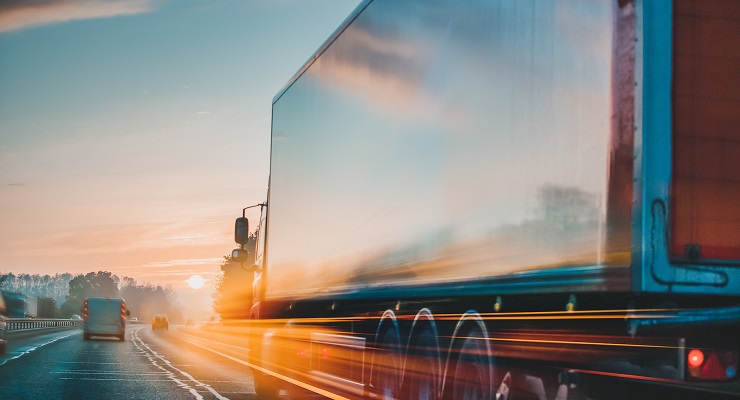 Two trucks on the road during sunset